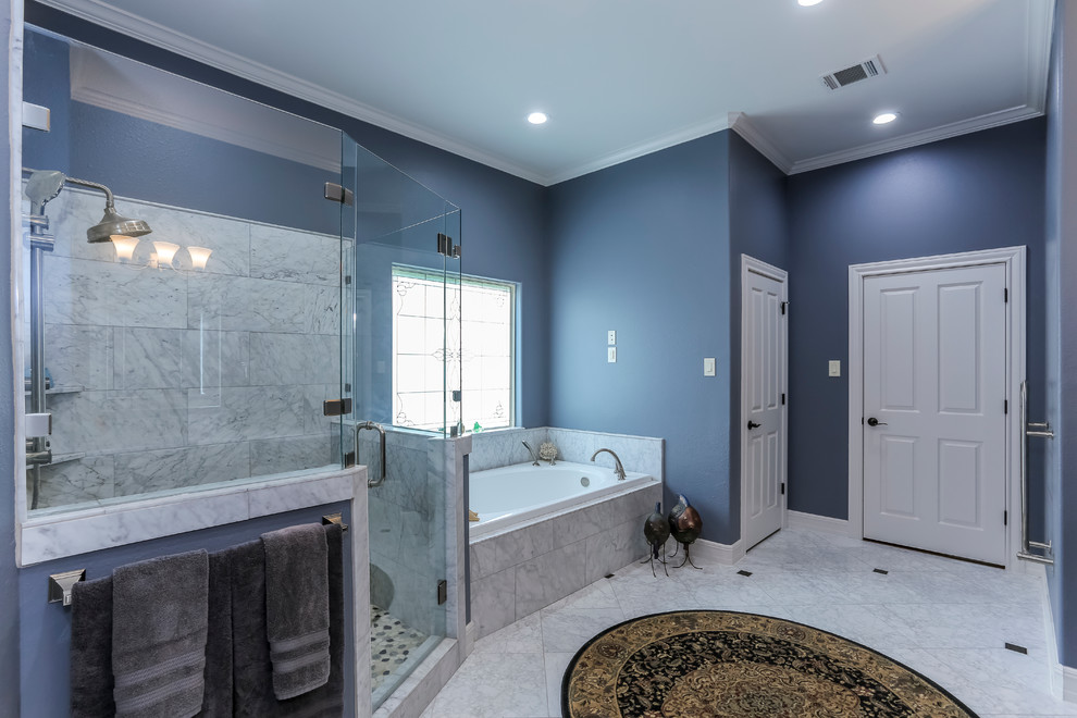 Aménagement d'une grande douche en alcôve principale classique avec un placard avec porte à panneau surélevé, une baignoire posée, un carrelage de pierre, un mur bleu, un sol en marbre, un lavabo encastré, un plan de toilette en marbre et des portes de placard noires.