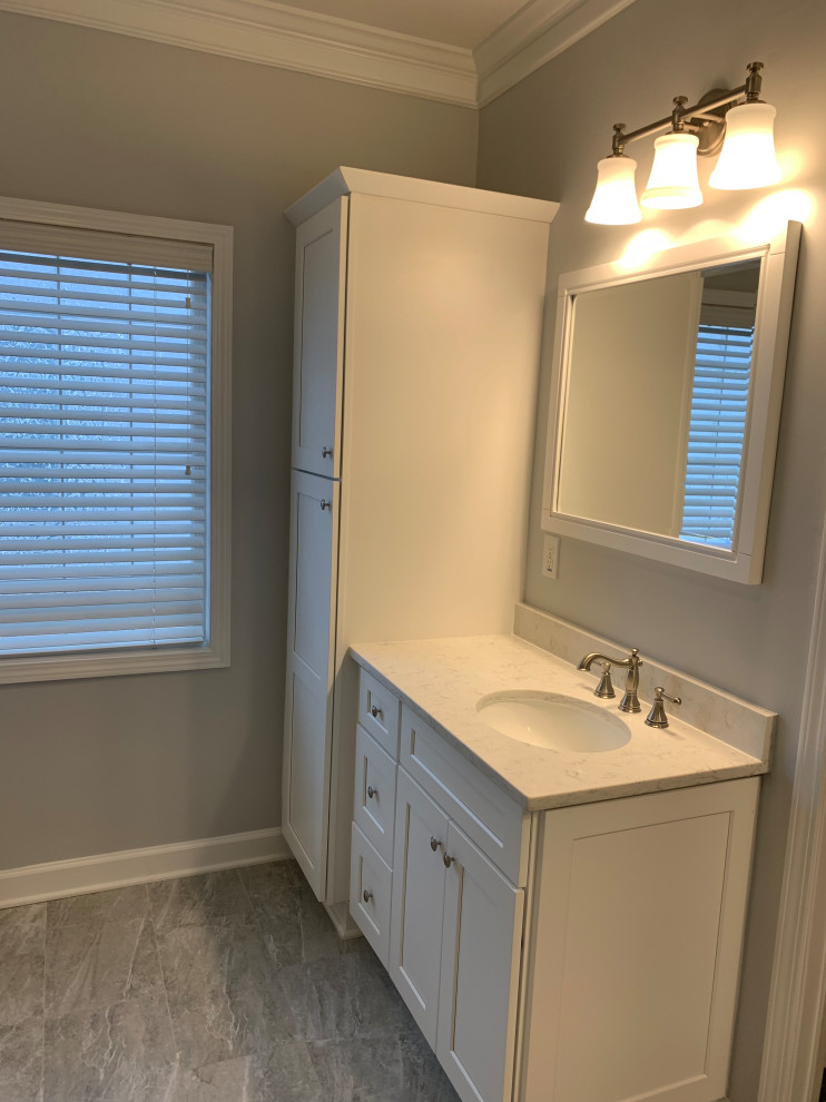 Photo of a medium sized traditional ensuite bathroom in Atlanta with shaker cabinets, white cabinets, a freestanding bath, a corner shower, a two-piece toilet, grey tiles, porcelain tiles, grey walls, terracotta flooring, a submerged sink, engineered stone worktops, grey floors, a hinged door and white worktops.