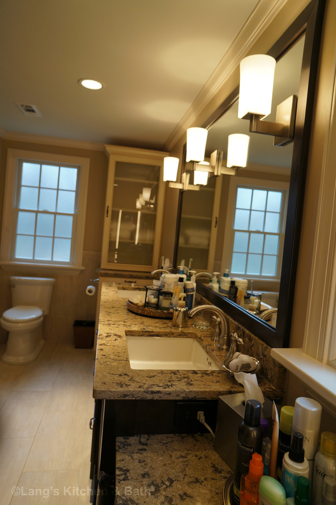 Large classic bathroom in Philadelphia with a submerged sink, freestanding cabinets, dark wood cabinets, engineered stone worktops, a built-in bath, a corner shower, a one-piece toilet, beige tiles, porcelain tiles, beige walls and porcelain flooring.