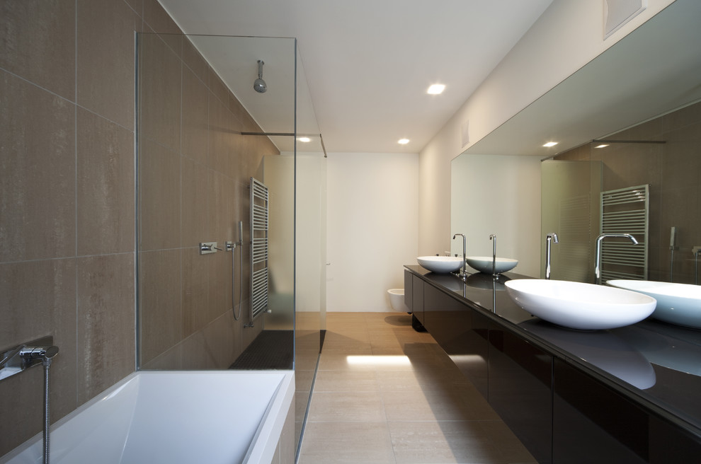 Modern inredning av ett stort en-suite badrum, med svarta skåp, ett hörnbadkar, en öppen dusch, stenkakel, vita väggar, skiffergolv, ett piedestal handfat, släta luckor, en vägghängd toalettstol och bänkskiva i glas