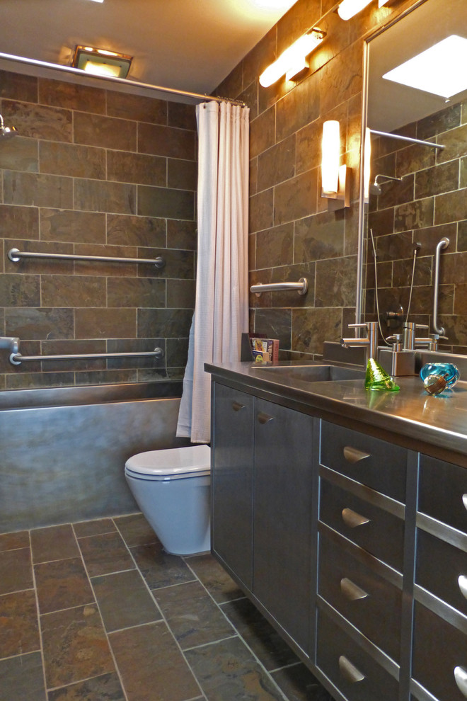 Inspiration för ett litet retro en-suite badrum, med ett integrerad handfat, släta luckor, grå skåp, bänkskiva i rostfritt stål, ett badkar i en alkov, en dusch/badkar-kombination, en toalettstol med hel cisternkåpa, grå kakel, stenkakel, gröna väggar och skiffergolv