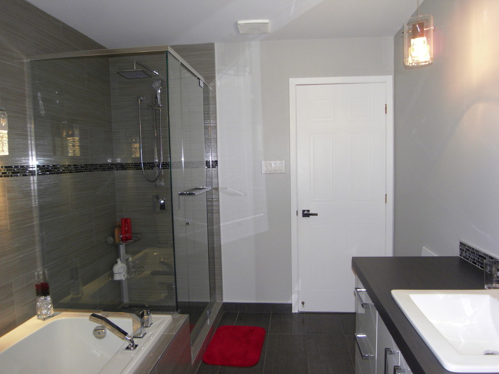 Inredning av ett modernt mellanstort en-suite badrum, med ett integrerad handfat, släta luckor, vita skåp, bänkskiva i kalksten, ett platsbyggt badkar, en dusch/badkar-kombination, en toalettstol med hel cisternkåpa, grå kakel, porslinskakel, grå väggar och klinkergolv i porslin