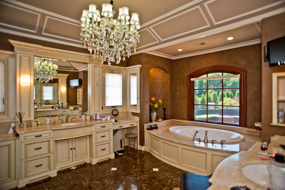 Cette photo montre une grande salle de bain principale victorienne avec un placard avec porte à panneau encastré, des portes de placard beiges, une baignoire posée, un mur marron, un sol en marbre, un lavabo encastré, un plan de toilette en granite et un sol marron.