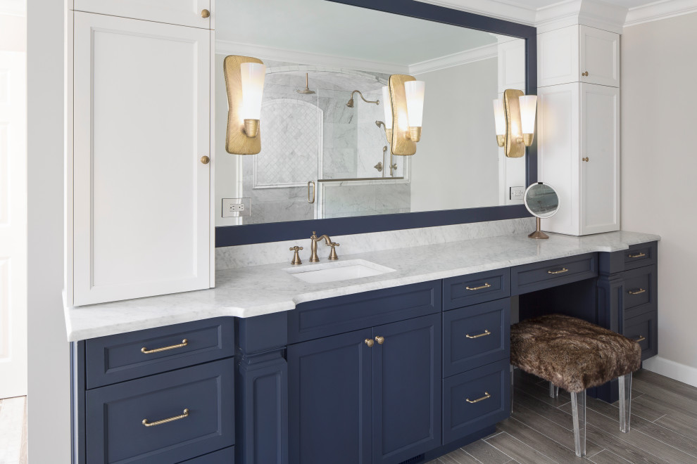 Bild på ett vit vitt badrum, med släta luckor, blå skåp, ett fristående badkar, gul kakel, marmorkakel, ett undermonterad handfat, marmorbänkskiva och grått golv