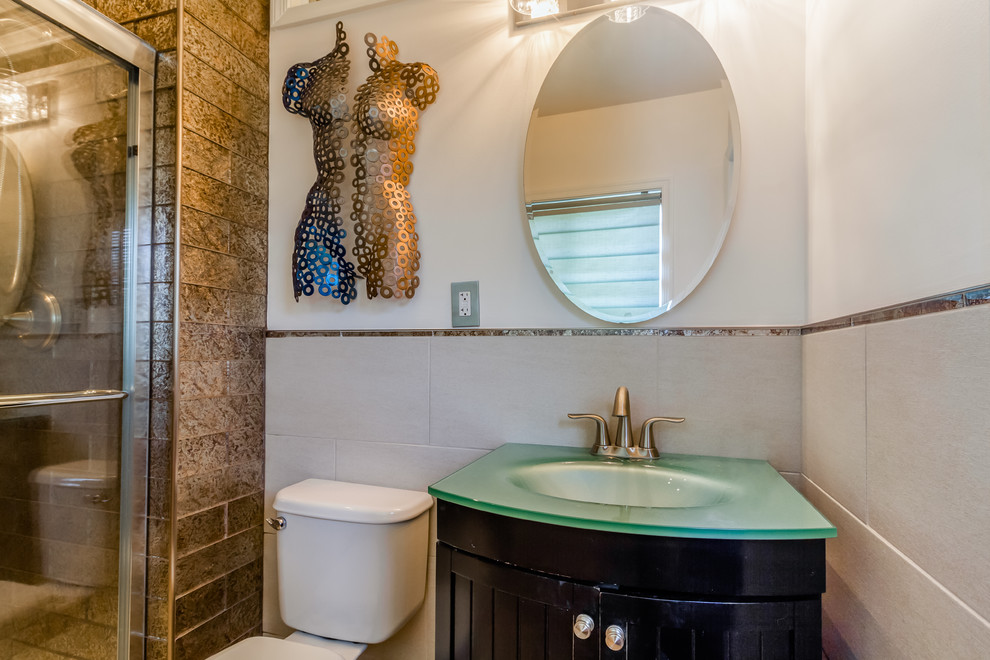 Стильный дизайн: ванная комната среднего размера в стиле неоклассика (современная классика) с темными деревянными фасадами, ванной в нише, душем в нише, раздельным унитазом, коричневой плиткой, металлической плиткой, белыми стенами, полом из керамогранита, душевой кабиной, монолитной раковиной, стеклянной столешницей, белым полом, душем с раздвижными дверями и зеленой столешницей - последний тренд