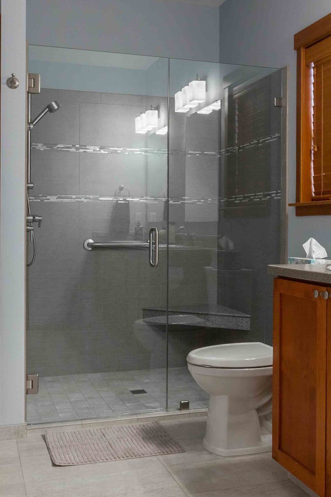 На фото: ванная комната в стиле фьюжн с фасадами в стиле шейкер, фасадами цвета дерева среднего тона, душем в нише, серой плиткой и серыми стенами