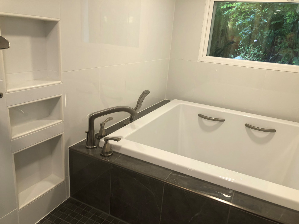 This is an example of a large modern ensuite wet room bathroom in Indianapolis with shaker cabinets, grey cabinets, a japanese bath, a bidet, white tiles, ceramic tiles, white walls, ceramic flooring, a submerged sink, engineered stone worktops, black floors, a hinged door, white worktops, a wall niche, double sinks and a freestanding vanity unit.