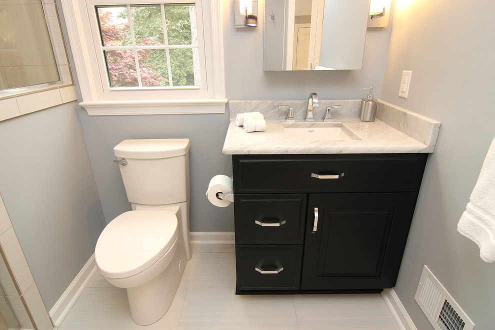 Example of a mid-sized minimalist master gray tile and porcelain tile porcelain tile alcove shower design in Other with an undermount sink, raised-panel cabinets, black cabinets, marble countertops, a two-piece toilet and blue walls