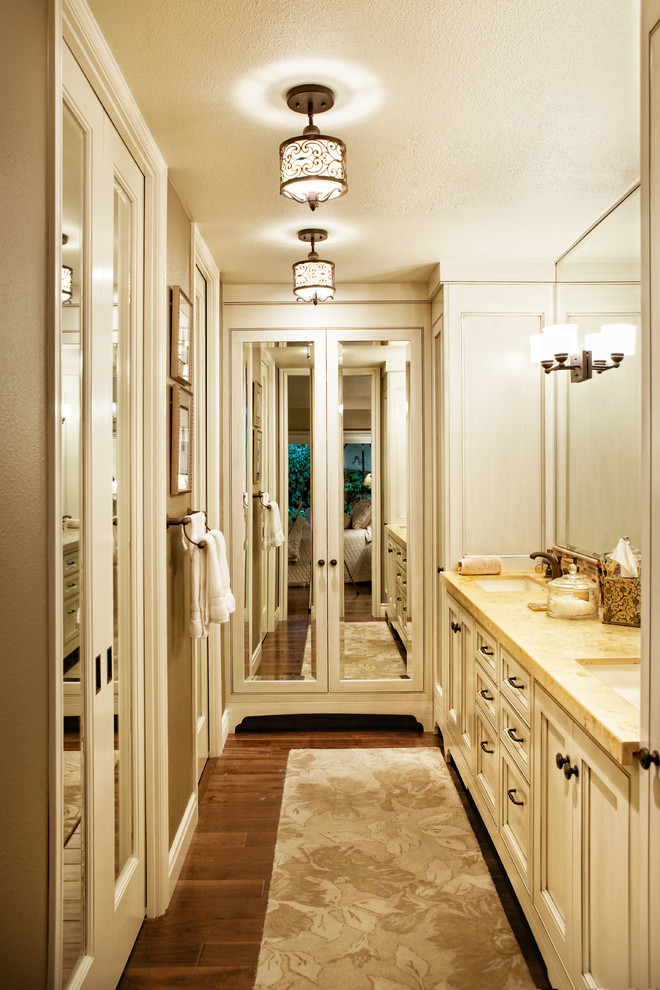 Immagine di una stanza da bagno padronale tradizionale di medie dimensioni con lavabo sottopiano, ante a filo, ante bianche, top in pietra calcarea, pareti beige e pavimento in legno massello medio