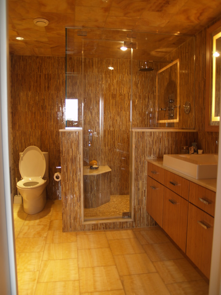 Medium sized contemporary shower room bathroom in New York with flat-panel cabinets, light wood cabinets, an alcove shower, a one-piece toilet, beige tiles, brown tiles, white tiles, brown walls, porcelain flooring, a vessel sink, solid surface worktops and matchstick tiles.