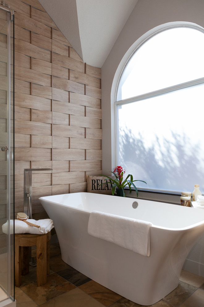 Modern inredning av ett mellanstort en-suite badrum, med ett avlångt handfat, ett fristående badkar, skiffergolv, släta luckor, skåp i mellenmörkt trä, en dusch i en alkov, beige kakel, skifferkakel, beige väggar och bänkskiva i akrylsten