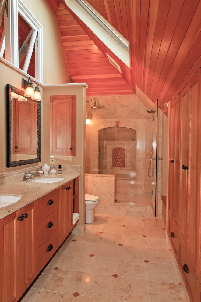 На фото: огромная главная ванная комната в стиле фьюжн с фасадами с утопленной филенкой, фасадами цвета дерева среднего тона, двойным душем, бежевой плиткой, каменной плиткой и столешницей из известняка