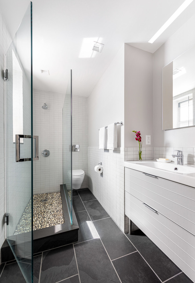 Idéer för små funkis vitt en-suite badrum, med grå skåp, ett badkar i en alkov, en dusch/badkar-kombination, en vägghängd toalettstol, grå kakel, cementgolv, bänkskiva i akrylsten och grått golv