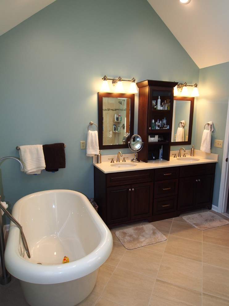 Exempel på ett stort klassiskt badrum, med ett undermonterad handfat, luckor med upphöjd panel, skåp i mörkt trä, bänkskiva i kvarts, ett fristående badkar, en dubbeldusch, en toalettstol med hel cisternkåpa, beige kakel, porslinskakel, blå väggar och kalkstensgolv