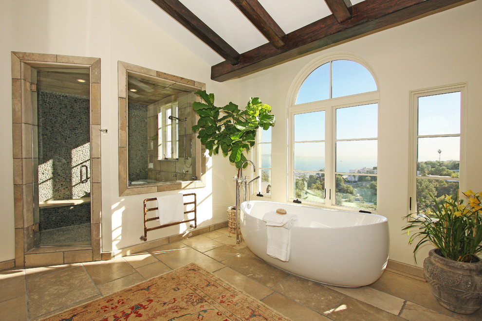 Exemple d'une très grande salle de bain principale chic avec une baignoire indépendante, une douche d'angle, une plaque de galets, un sol en travertin, WC à poser, un carrelage beige, un mur blanc, un lavabo encastré et une fenêtre.