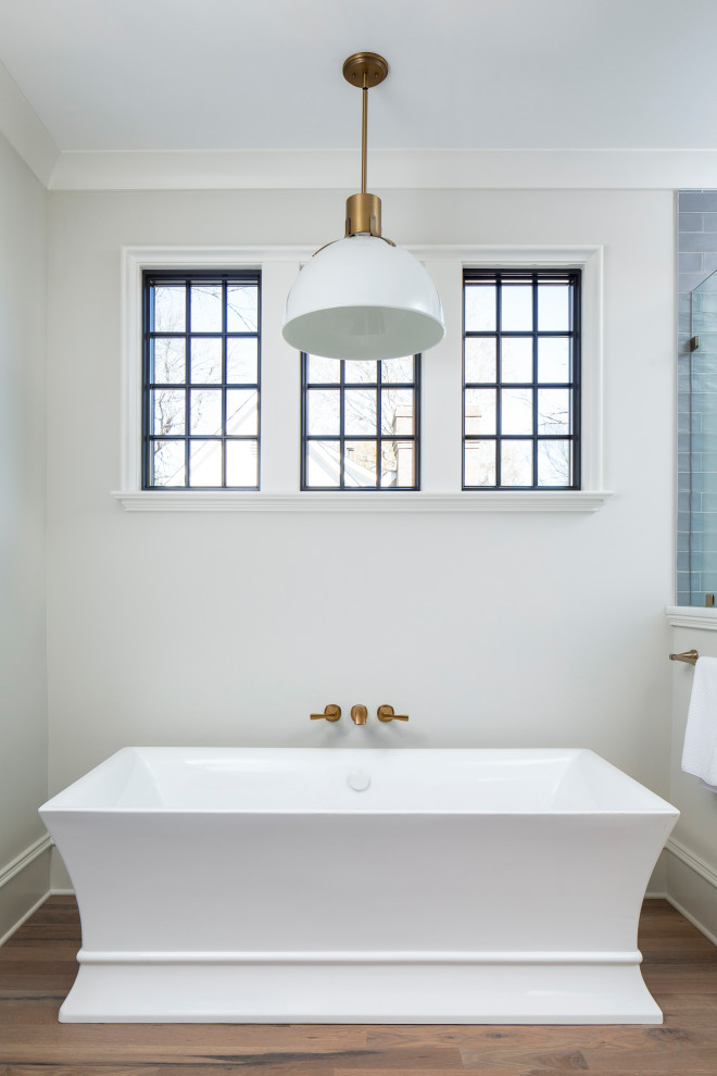 Imagen de cuarto de baño principal clásico renovado de tamaño medio con bañera exenta, paredes beige, suelo de madera en tonos medios, encimera de mármol, suelo marrón y encimeras blancas
