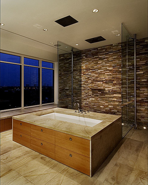 Cette photo montre une salle de bain principale moderne en bois brun avec une vasque, un placard sans porte, un plan de toilette en calcaire, une baignoire encastrée, une douche ouverte, WC à poser, un carrelage de pierre et un sol en calcaire.