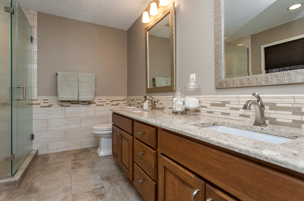 Medium sized traditional ensuite bathroom in Other with raised-panel cabinets, medium wood cabinets, a freestanding bath, a corner shower, a two-piece toilet, beige tiles, ceramic tiles, beige walls, ceramic flooring, a submerged sink, engineered stone worktops, beige floors, a hinged door and beige worktops.
