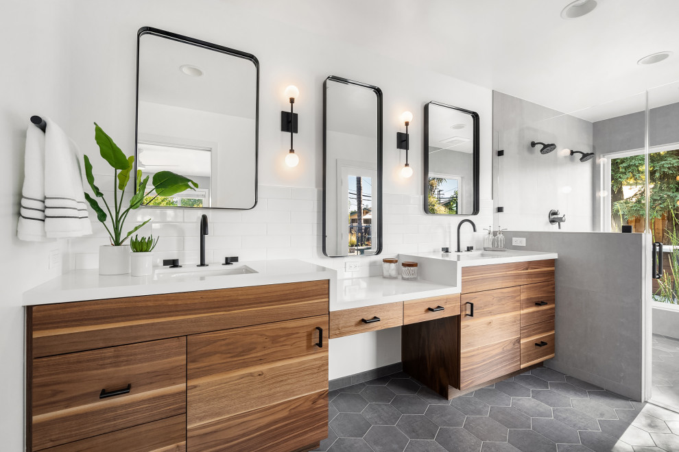 Photo of a contemporary ensuite bathroom in San Francisco with flat-panel cabinets, medium wood cabinets, a double shower, metro tiles, a submerged sink, grey floors, a hinged door, white worktops, double sinks and a built in vanity unit.
