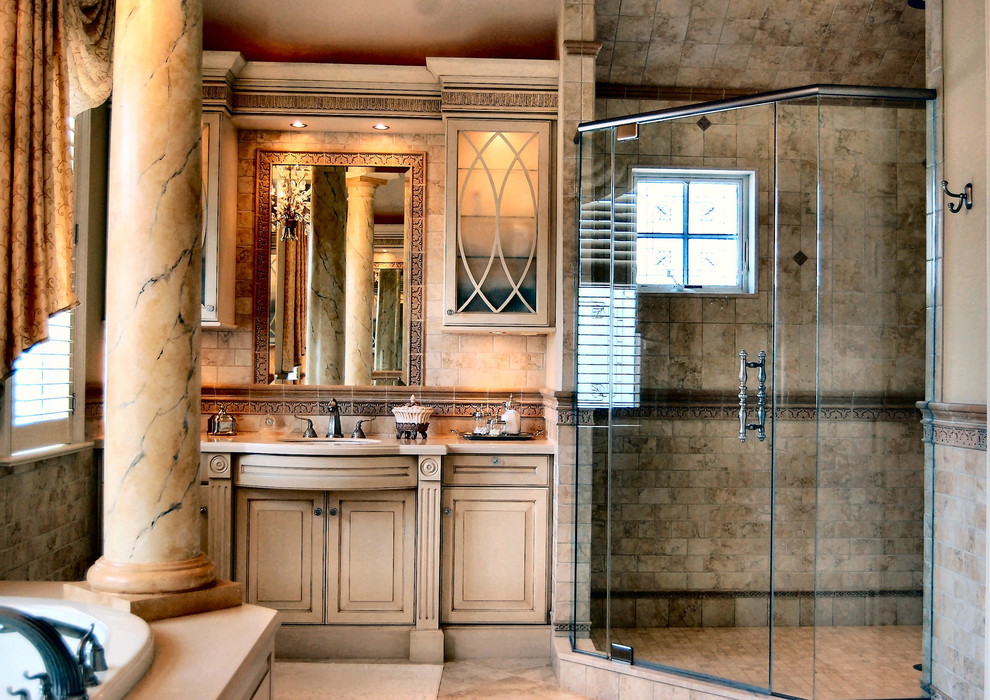 Example of a large classic master beige tile and ceramic tile limestone floor and beige floor bathroom design in Philadelphia with raised-panel cabinets, beige cabinets, an undermount sink, marble countertops, beige walls and a hinged shower door