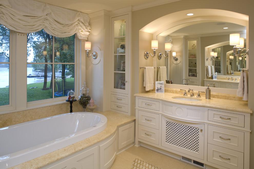 Cette photo montre une grande salle de bain principale chic avec une baignoire posée, des portes de placard beiges, un plan de toilette en granite, un carrelage beige, des carreaux de céramique et un sol en carrelage de céramique.