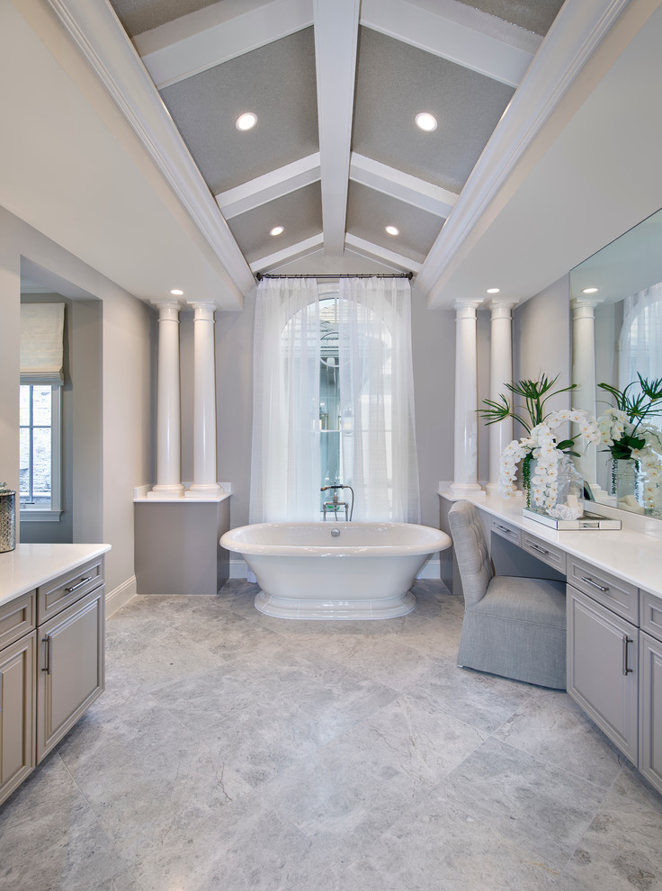 Стильный дизайн: главная, серо-белая ванная комната в классическом стиле с фасадами с выступающей филенкой, серыми фасадами, отдельно стоящей ванной и серыми стенами - последний тренд