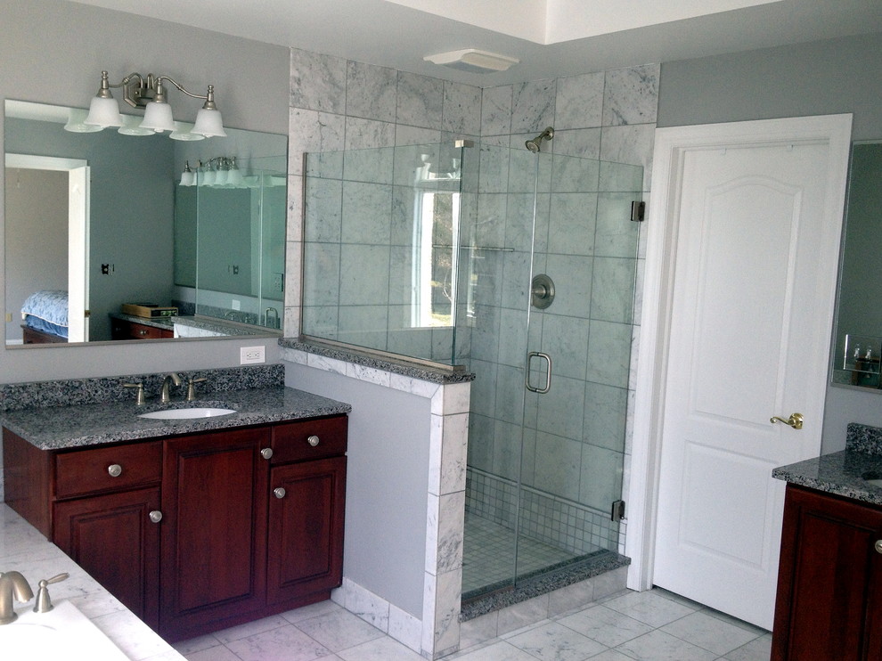 Bathroom - mid-sized transitional master ceramic tile and white floor bathroom idea in Philadelphia with raised-panel cabinets, dark wood cabinets, gray walls, an undermount sink, granite countertops, a hinged shower door and multicolored countertops
