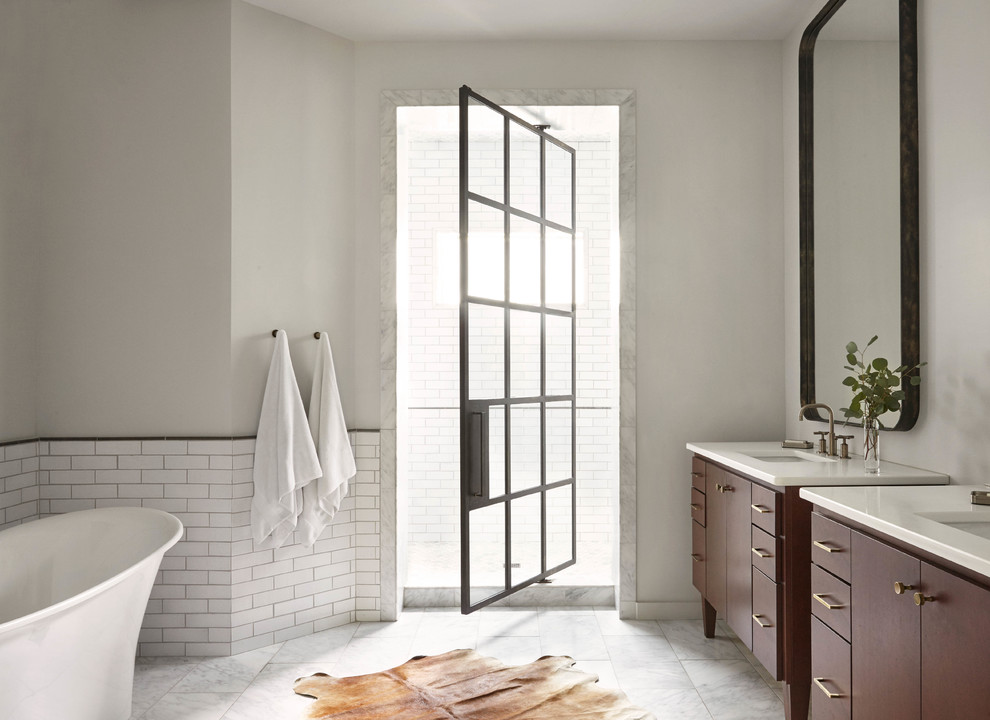 Photo of a large contemporary ensuite bathroom in Nashville with medium wood cabinets, a freestanding bath, white tiles, metro tiles, white walls, marble flooring, a submerged sink, quartz worktops, white floors, an alcove shower and flat-panel cabinets.