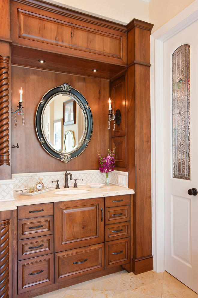 Bild på ett vintage en-suite badrum, med bruna skåp, bänkskiva i onyx, ett badkar med tassar, en dusch i en alkov, beige kakel, stenkakel, beige väggar och kalkstensgolv
