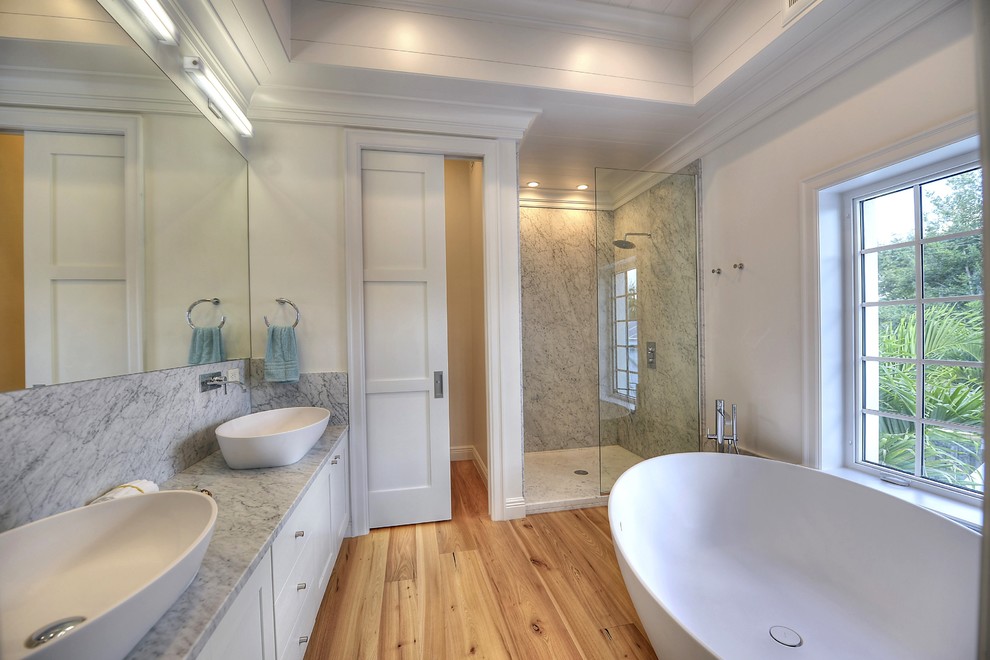 Modelo de cuarto de baño principal actual grande con puertas de armario blancas y encimera de mármol