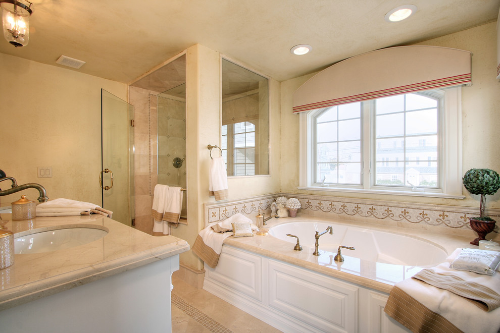 Mid-sized tuscan master beige tile and ceramic tile ceramic tile corner shower photo in Philadelphia with raised-panel cabinets, white cabinets, beige walls, a drop-in sink and granite countertops