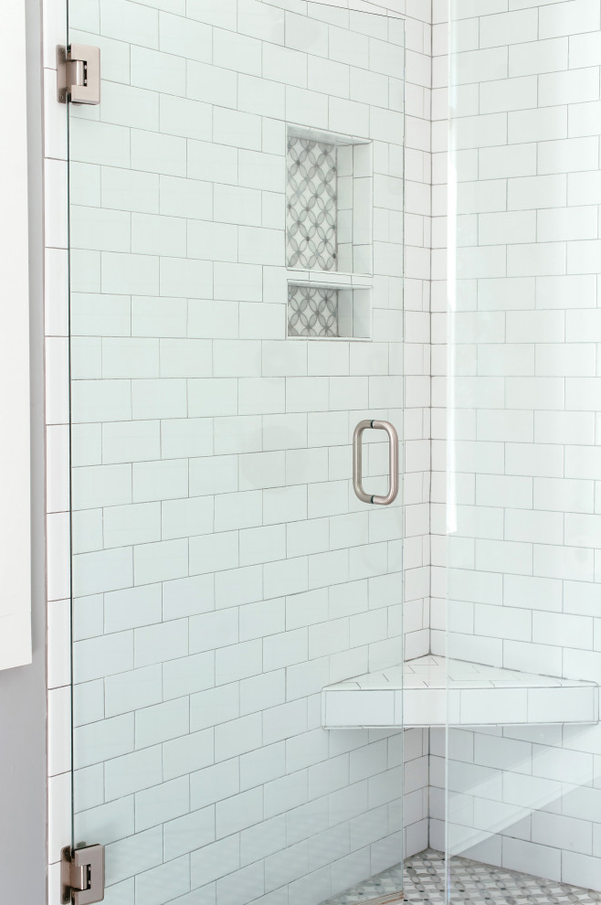 На фото: главная ванная комната среднего размера в классическом стиле с фасадами в стиле шейкер, серыми фасадами, душем в нише, унитазом-моноблоком, белой плиткой, плиткой кабанчик, белыми стенами, паркетным полом среднего тона, врезной раковиной, столешницей из искусственного кварца, коричневым полом, душем с распашными дверями, белой столешницей, сиденьем для душа, тумбой под две раковины и напольной тумбой с