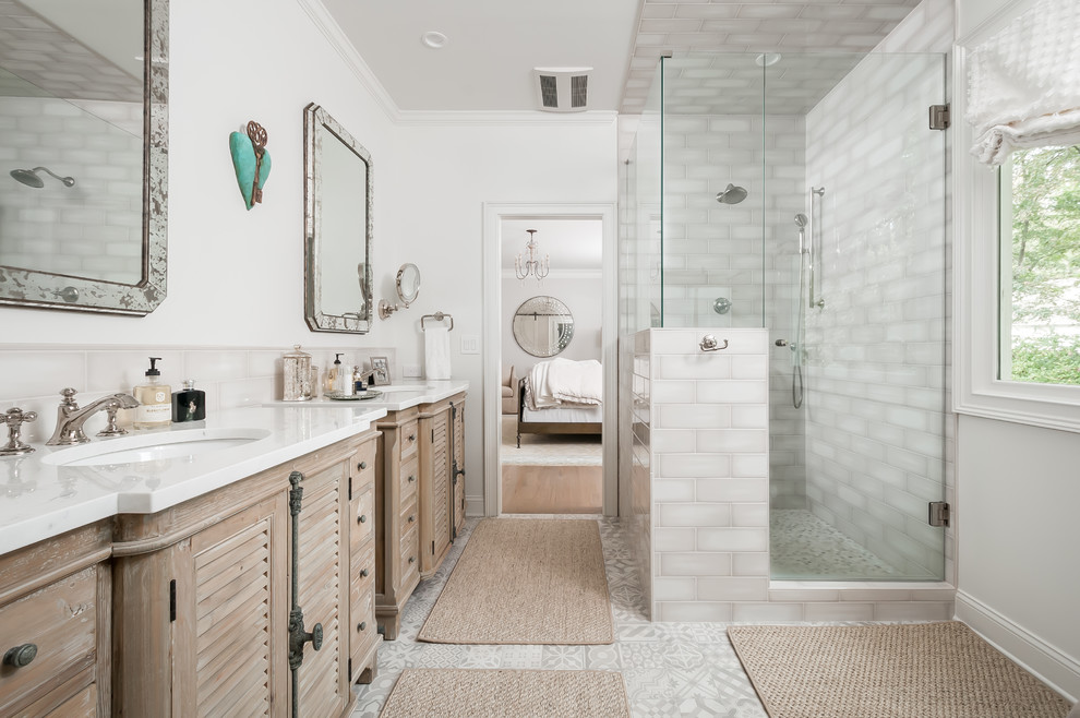 Cette image montre une grande salle de bain principale rustique en bois clair avec un placard à porte persienne, une douche d'angle, un carrelage beige, un mur blanc, un lavabo encastré, un sol gris, une cabine de douche à porte battante et un plan de toilette blanc.