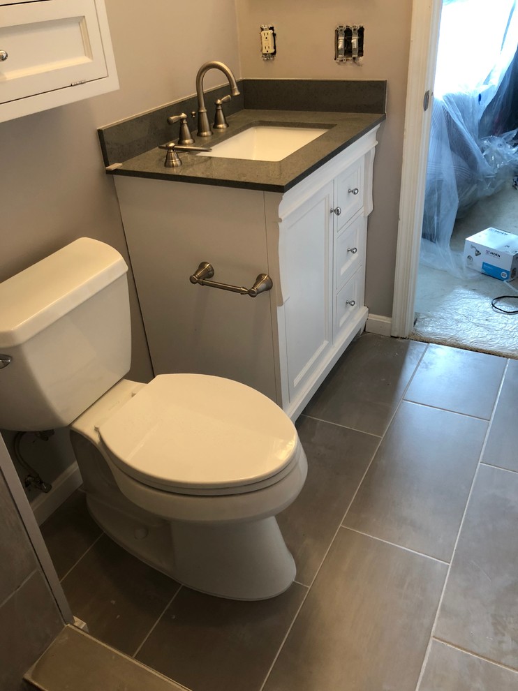 Cette photo montre une petite salle de bain pour enfant avec un placard à porte shaker, des portes de placard blanches, WC à poser, un carrelage marron, des carreaux de céramique, un mur gris, un sol en carrelage de céramique, un lavabo encastré, un plan de toilette en granite, un sol gris et un plan de toilette gris.