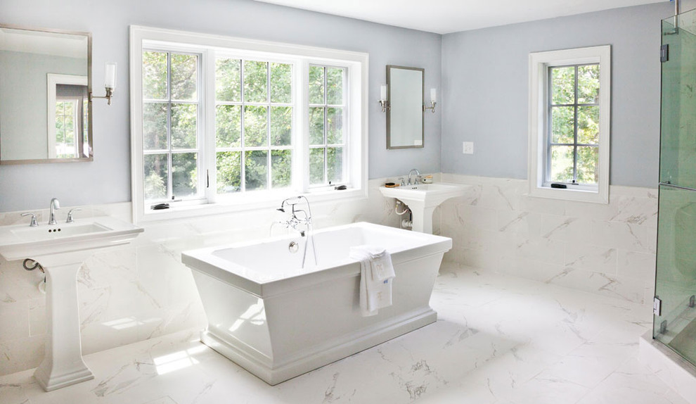 Inredning av ett klassiskt stort en-suite badrum, med ett piedestal handfat, ett fristående badkar, en hörndusch, vit kakel, porslinskakel, blå väggar och klinkergolv i porslin