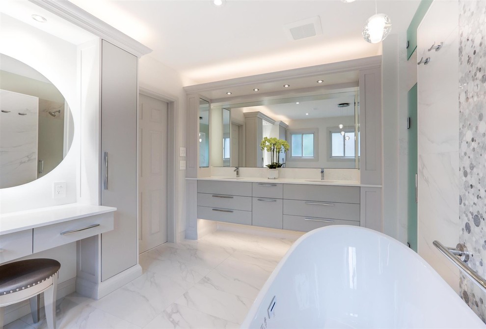 Cette image montre une salle de bain principale design de taille moyenne avec un placard à porte shaker, des portes de placard blanches, une baignoire indépendante, un carrelage blanc, du carrelage en marbre, un mur gris, un sol en marbre, un lavabo encastré, un plan de toilette en quartz modifié et un plan de toilette blanc.