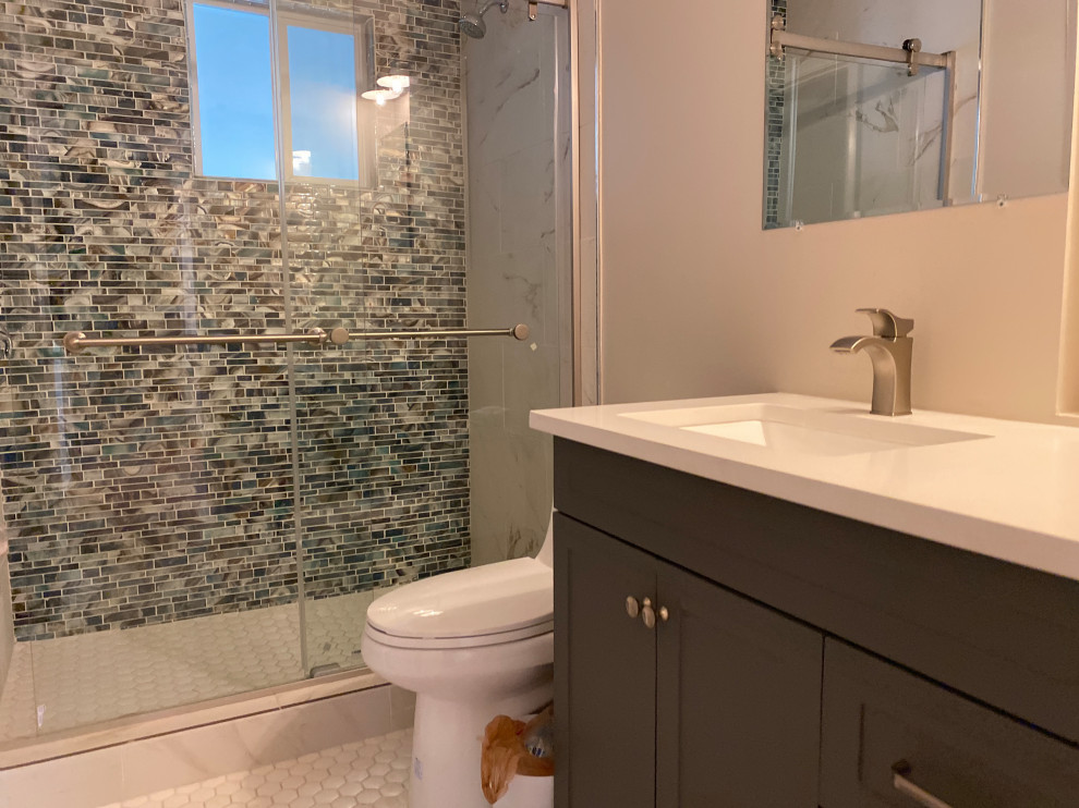 Photo of a medium sized contemporary ensuite bathroom in Denver with shaker cabinets, brown cabinets, a one-piece toilet, beige tiles, ceramic tiles, beige walls, ceramic flooring, a submerged sink, quartz worktops, grey floors, a sliding door, beige worktops, a single sink, a freestanding vanity unit and a coffered ceiling.