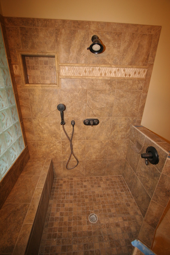 На фото: главная ванная комната среднего размера в классическом стиле с фасадами с выступающей филенкой, фасадами цвета дерева среднего тона, угловым душем, бежевой плиткой, коричневой плиткой, керамической плиткой, бежевыми стенами, полом из керамической плитки, накладной раковиной, столешницей из ламината, бежевым полом и душем с распашными дверями с