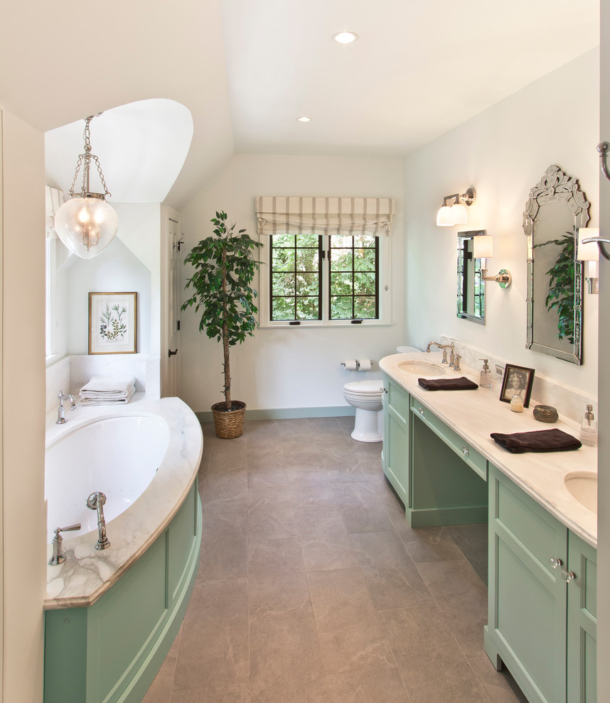 На фото: ванная комната в классическом стиле с врезной раковиной, фасадами с утопленной филенкой, зелеными фасадами, раздельным унитазом и полновстраиваемой ванной с