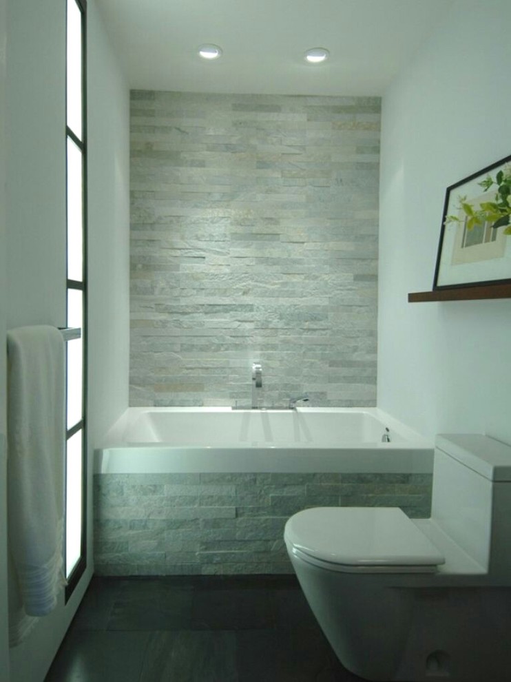 Ejemplo de cuarto de baño moderno con bañera empotrada, baldosas y/o azulejos grises, baldosas y/o azulejos de piedra, paredes blancas y suelo gris