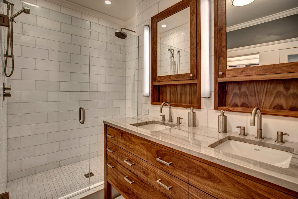 Amerikansk inredning av ett en-suite badrum, med ett undermonterad handfat, släta luckor, skåp i mellenmörkt trä och en dusch i en alkov