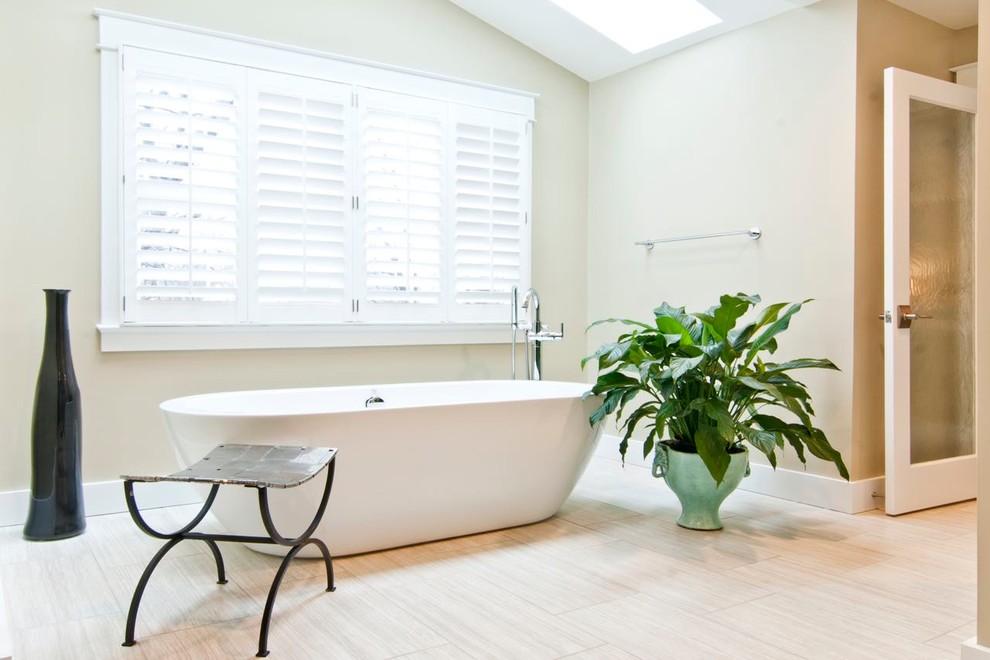Foto på ett mellanstort funkis en-suite badrum, med ett fristående badkar, beige kakel, keramikplattor, beige väggar och klinkergolv i porslin