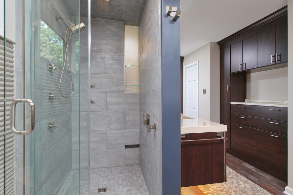 Inspiration for a large modern master gray tile, white tile and stone tile medium tone wood floor alcove shower remodel in Philadelphia with flat-panel cabinets, dark wood cabinets, a two-piece toilet, white walls, an integrated sink and solid surface countertops