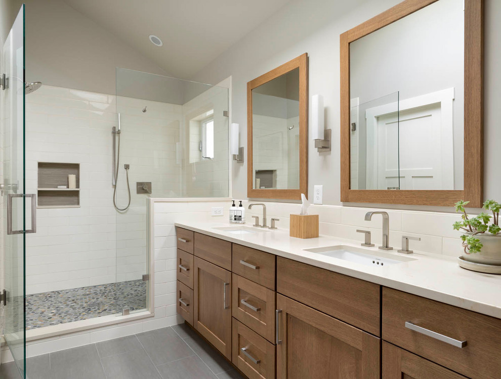 Cette image montre une salle de bain craftsman en bois brun de taille moyenne avec un placard avec porte à panneau encastré, une douche double, un lavabo encastré et un sol gris.