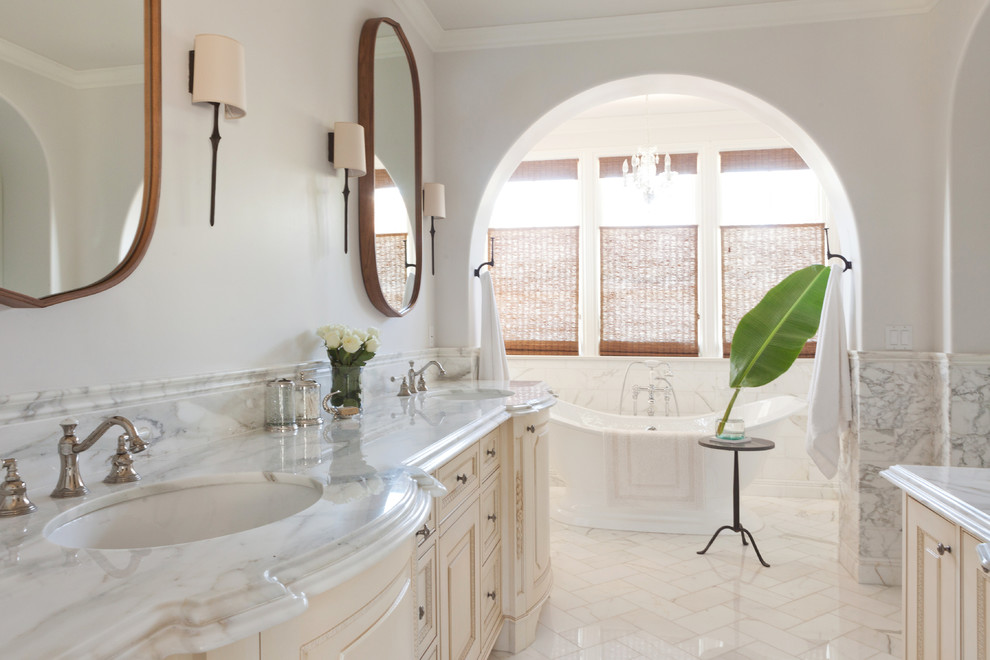 Idéer för ett stort medelhavsstil en-suite badrum, med luckor med profilerade fronter, skåp i ljust trä, ett fristående badkar, en dusch i en alkov, en toalettstol med hel cisternkåpa, vit kakel, stenkakel, vita väggar, marmorgolv, ett undermonterad handfat och marmorbänkskiva