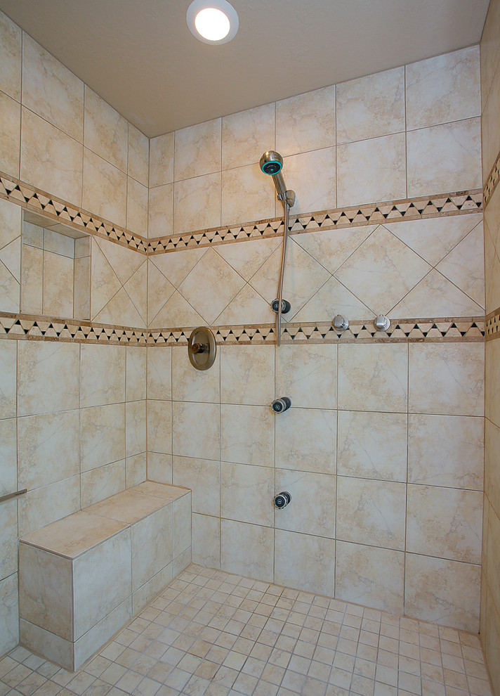 Cette image montre une très grande salle de bain principale traditionnelle en bois brun avec un placard à porte shaker, un carrelage beige, un mur beige, un lavabo posé et un plan de toilette en quartz modifié.
