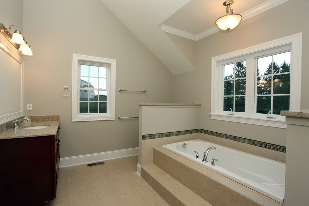 Imagen de cuarto de baño tradicional con bañera encastrada, puertas de armario de madera en tonos medios, encimera de granito, baldosas y/o azulejos de porcelana, paredes beige y suelo de baldosas de porcelana