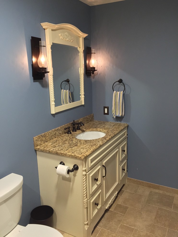 Cette photo montre une petite douche en alcôve principale tendance en bois clair avec un placard avec porte à panneau encastré, WC séparés, un carrelage beige, des carreaux de porcelaine, un mur bleu, un sol en carrelage de porcelaine, un lavabo encastré et un plan de toilette en granite.
