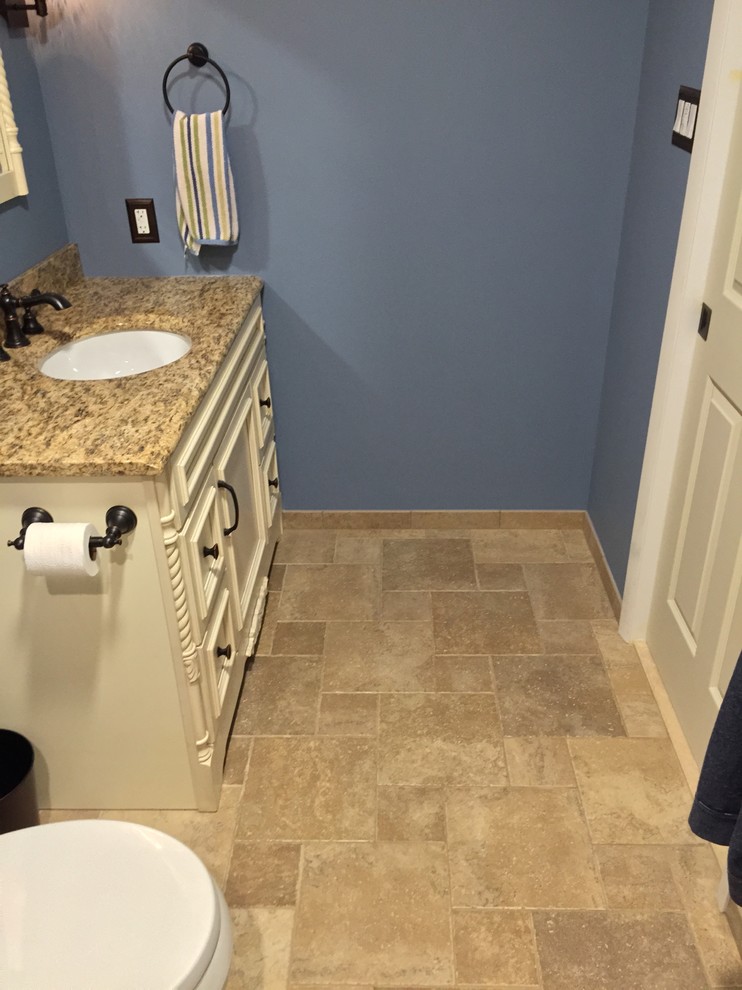 Photo of a small contemporary ensuite bathroom in Philadelphia with recessed-panel cabinets, light wood cabinets, an alcove shower, a two-piece toilet, beige tiles, porcelain tiles, blue walls, porcelain flooring, a submerged sink and granite worktops.