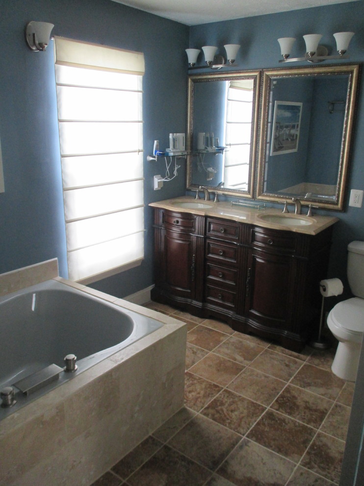 Mid-sized trendy stone tile porcelain tile drop-in bathtub photo in DC Metro with a console sink, furniture-like cabinets, medium tone wood cabinets, granite countertops, a two-piece toilet and blue walls